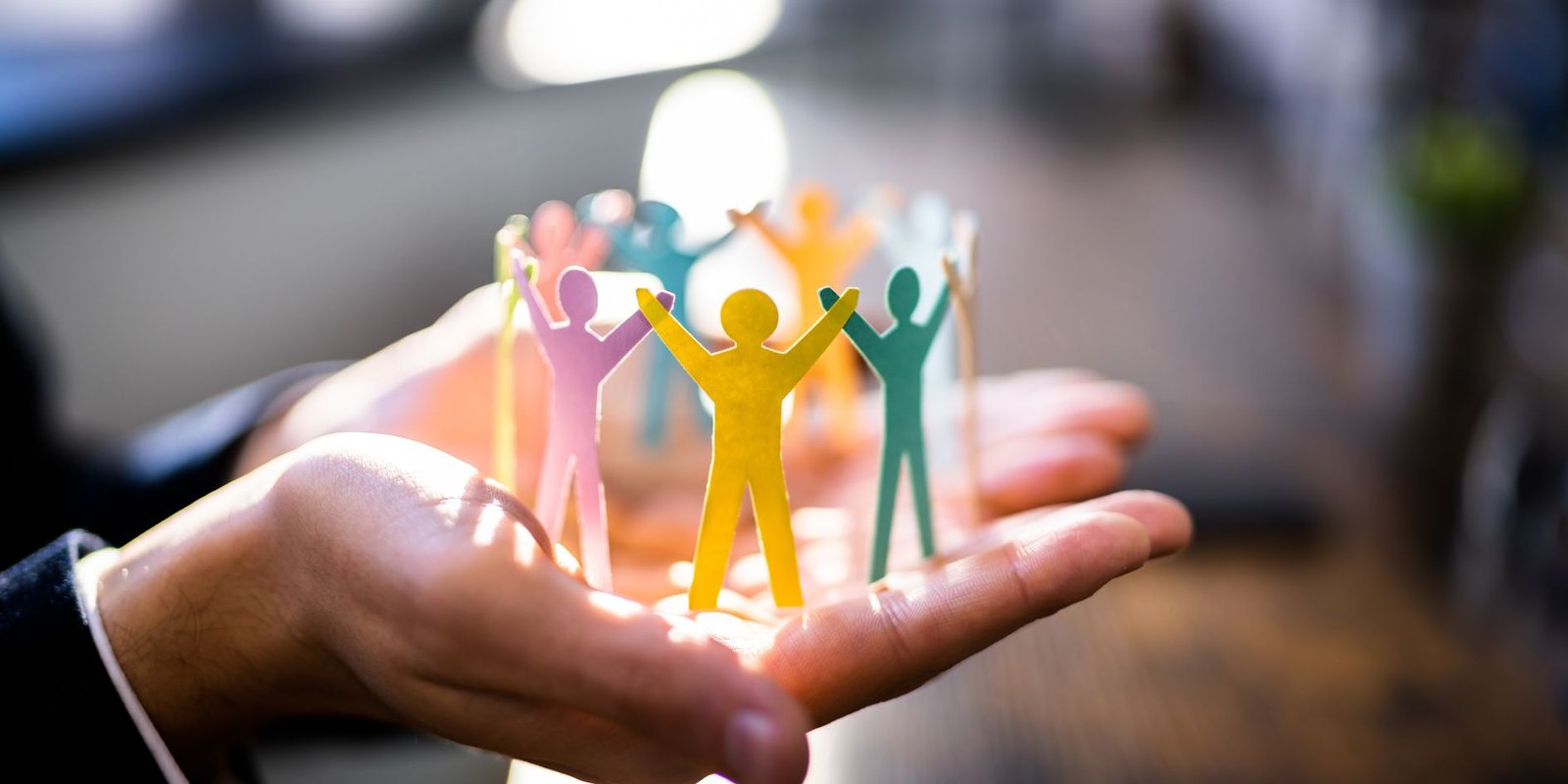 hands holding paper cut outs of people